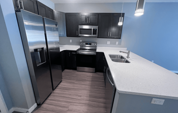 A modern kitchen with a stainless steel refrigerator and black cabinets.